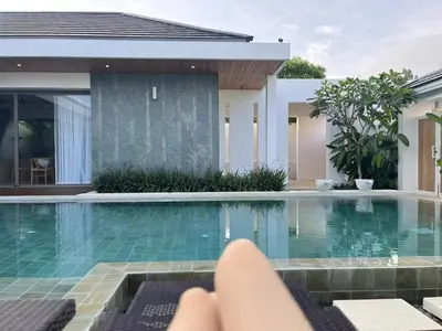 a person laying on a chair in front of a swimming pool at 3 Bed Bang Tao pool villa at The Lux in Phuket Town