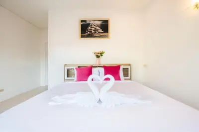 two white swans in a white bed with pink pillows at Fora Boutique Hotel in Karon Beach