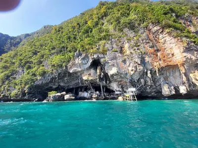a boat in front of a cave in the water at Fora Boutique Hotel in Karon Beach