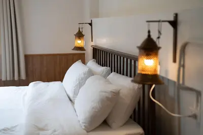 a bed with white pillows and two lights on it at Baan Old Town Boutique Stay, Phuket Town in Phuket Town