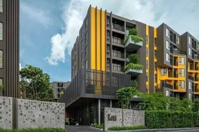 a yellow and gray building with trees in front of it at PRIME TOWN Phuket Resort & Wellness in Ban Rangeng