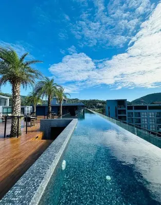 a swimming pool on the roof of a building with palm trees at Citygate Kamala Resort & Residence in Kamala Beach