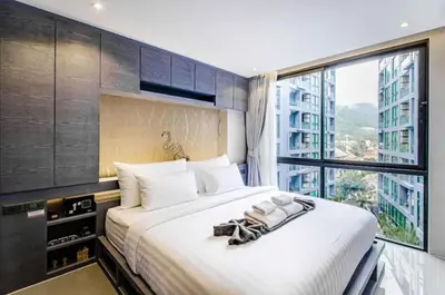 a bedroom with a large bed with a large window at Citygate Kamala Resort & Residence in Kamala Beach