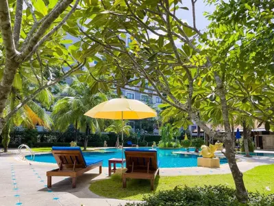 two chairs and a table with an umbrella next to a pool at Ongsantiphap villa resort in Ban Klang