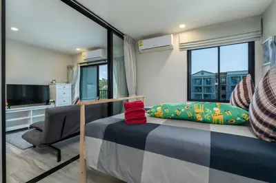 a bedroom with a bed and a chair and a window at A1 The Title Nayang Стильная квартира in Nai Yang Beach