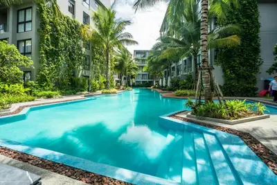 a swimming pool in the middle of a building with palm trees at Modern 2br apartment near Bangtao beach in Bang Tao Beach