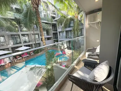 a balcony with a swimming pool and palm trees at Modern 2br apartment near Bangtao beach in Bang Tao Beach
