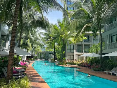 a swimming pool with palm trees and buildings at Modern 2br apartment near Bangtao beach in Bang Tao Beach