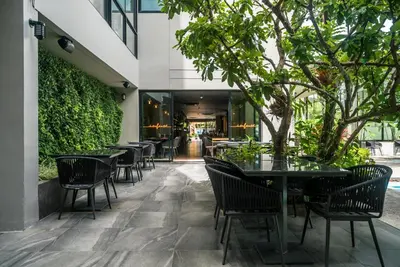 an outdoor patio with tables and chairs and trees at Modern 2br apartment near Bangtao beach in Bang Tao Beach