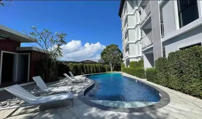 a swimming pool with chairs and a building at Title Rent Rawai in Rawai Beach