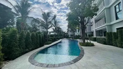 a swimming pool in front of a building with trees at Title Rent Rawai in Rawai Beach
