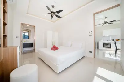 a white bedroom with a white bed and a ceiling fan at Sea & Mountain Views Apartment at VV Patong A603 in Patong Beach