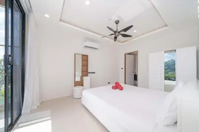 a white bedroom with a bed and a ceiling fan at Sea & Mountain Views Apartment at VV Patong A603 in Patong Beach