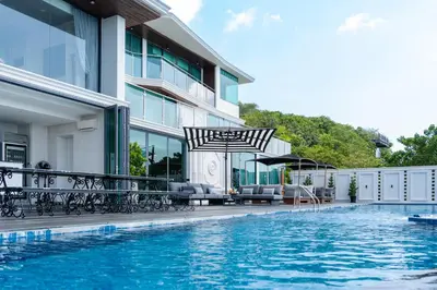 a pool with chairs and an umbrella next to a building at Villa W Luxury in Nai Harn Beach
