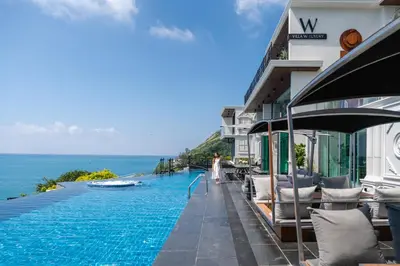 a swimming pool next to a building with the ocean at Villa W Luxury in Nai Harn Beach