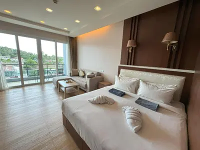 a bedroom with a large bed and a living room at Spacious mountain view studio at Sea Sky 206 in Karon Beach