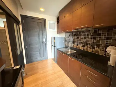 a kitchen with wooden cabinets and a black refrigerator at Spacious mountain view studio at Sea Sky 206 in Karon Beach