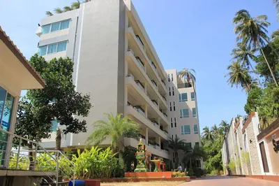 a white building with palm trees in front of it at Spacious mountain view studio at Sea Sky 206 in Karon Beach
