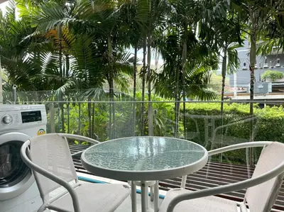 a glass table and two chairs on a balcony at Peaceful Rawai studio with washer by Lofty in Rawai Beach