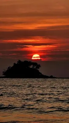 a sunset over an island in the ocean at Stylish Apartment with Workspace 10 Minutes from the Beach for min 30 Day Stays in Phuket Town