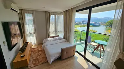 a bedroom with a bed and a balcony with a view at Stylish Apartment with Workspace 10 Minutes from the Beach for min 30 Day Stays in Phuket Town