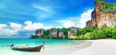 a boat on a beach with rocks in the water at XX Bao Pathong Beach เบา ภูเก็ต หาดป่าตอง in Patong Beach