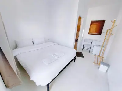 a white bedroom with a white bed and a chair at XX Bao Pathong Beach เบา ภูเก็ต หาดป่าตอง in Patong Beach