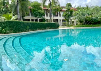 a swimming pool with blue water in front of a building at Laguna Village by RESAVA in Layan Beach