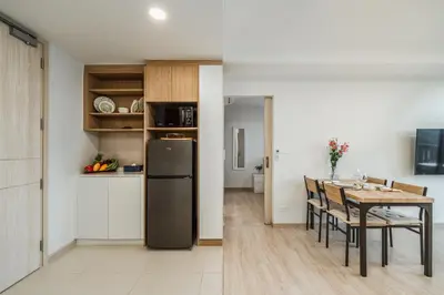 a kitchen and dining room with a table and a refrigerator at Идеальные апартаменты в Laguna Skypark in Phuket Town