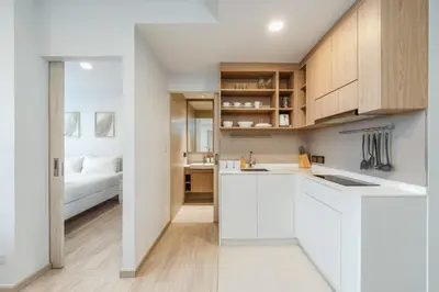 a kitchen with white cabinets and a bed in the background at Идеальные апартаменты в Laguna Skypark in Phuket Town
