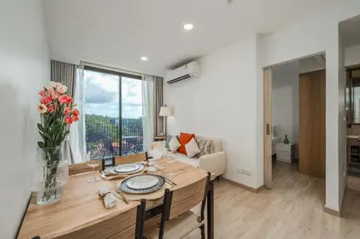 a dining room table with a vase of flowers at Идеальные апартаменты в Laguna Skypark in Phuket Town