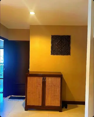 a room with a yellow wall and a wooden cabinet at Patong Tower Apartments By Tida in Patong Beach