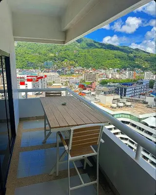 a wooden table and a chair on a balcony at Patong Tower Apartments By Tida in Patong Beach