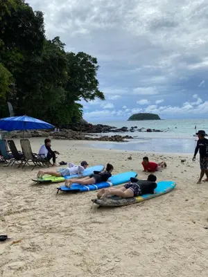a group of people laying on surfboards on a beach at Sea View One Bedroom Condo in Kata Beach in Kata Beach