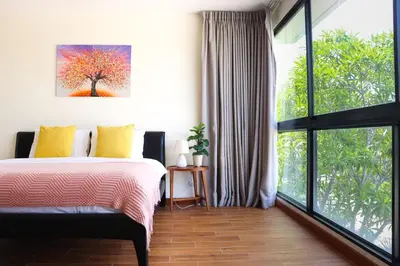 a bedroom with a bed and a large window at Big Garden Townhouse Laguna Park in Phuket Town