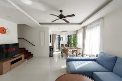 a living room with a blue couch and a ceiling fan at Big Garden Townhouse Laguna Park in Phuket Town