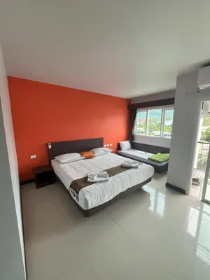 a bedroom with a large bed and an orange wall at Chollada Inn in Kamala Beach