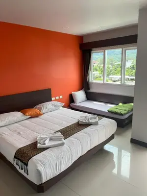 two beds in a room with orange walls and windows at Chollada Inn in Kamala Beach