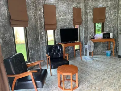 a living room with furniture and a tv and windows at Green Tree Cottage 1 in Klong Muang Beach