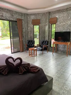 a bedroom with a bed and a television and a piano at Green Tree Cottage 1 in Klong Muang Beach