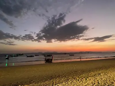 a beach with boats in the water at sunset at Green Tree Cottage 2 in Klong Muang Beach