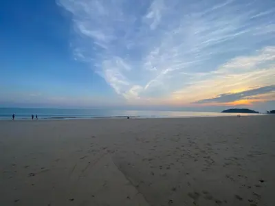 a beach with people walking on the sand at Green Tree Cottage 2 in Klong Muang Beach