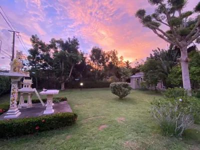 a garden with a bench and a sunset in the background at Green Tree Cottage 2 in Klong Muang Beach