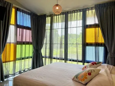 a bedroom with a bed and large windows at Moonlight Cottage in Ban Pa Khlok