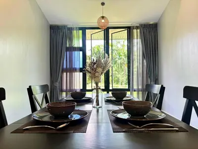 a dining room table with chairs and a large window at Moonlight Cottage in Ban Pa Khlok