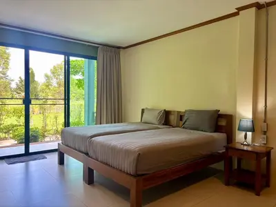 a bedroom with a large bed and a large window at Moonlight Cottage in Ban Pa Khlok