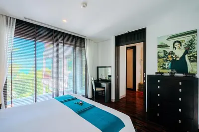 a bedroom with a bed and a desk and a window at Luxury Penthouse Apartment 8C at Kata Gardens in Kata Beach