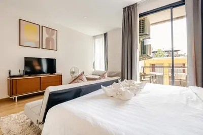 a bedroom with a white bed and a tv at The Proud Rawai Studio in Phuket Town
