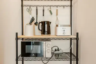 a black shelf with a microwave and utensils at The Proud Rawai Studio in Phuket Town