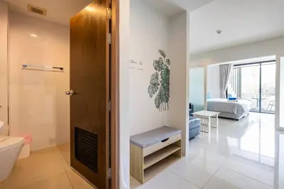 a bathroom with a toilet and a room with a bed at The Pixels Cape Panwa Condo in Ban Ao Makham